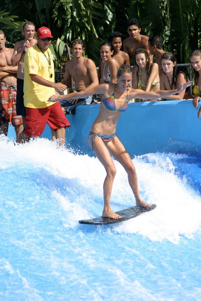 Da Flowrider a group of people watching a girl in a Bikini surf Da Flowrider