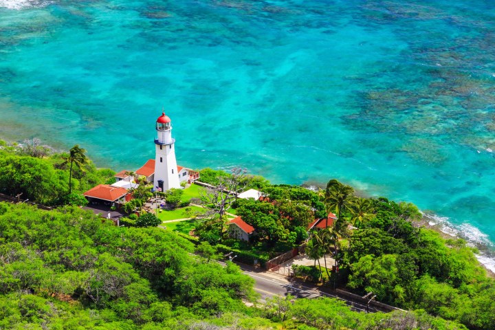 a fire hydrant next to a body of water with Diamond Head Lighthouse in the background
