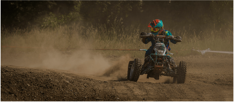 blog4 Person riding an ATV on a dirt track, kicking up dust.