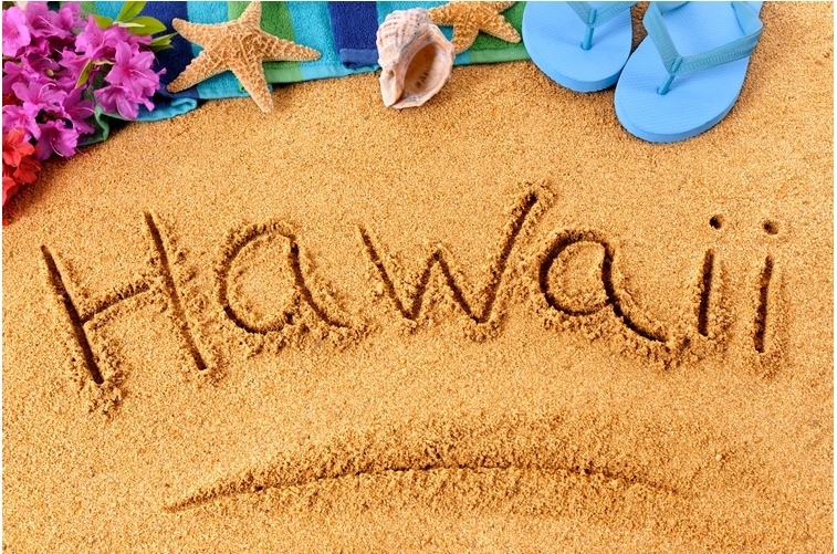 blog_3f200e Word 'Hawaii' written in sand with flowers, starfish, shell, and blue flip-flops nearby.