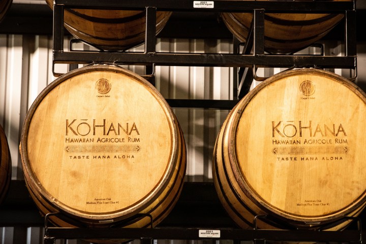 Two wooden barrels labeled 'Kohana Hawaiian Agricole Rum' on a metal rack.